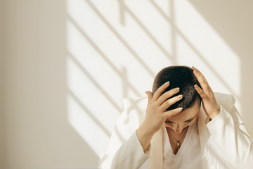 Woman with her hands on her head in front of window lighting