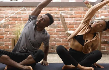 Two people practicing yoga poses together outdoors.