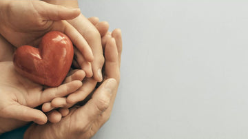 2 pairs of hands holding a ceramic heart
