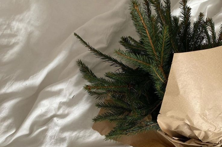 Greenery in kraft paper wrapping on a bed