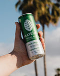 Mateina Yerba Mate Can in a hand with palm trees in the background